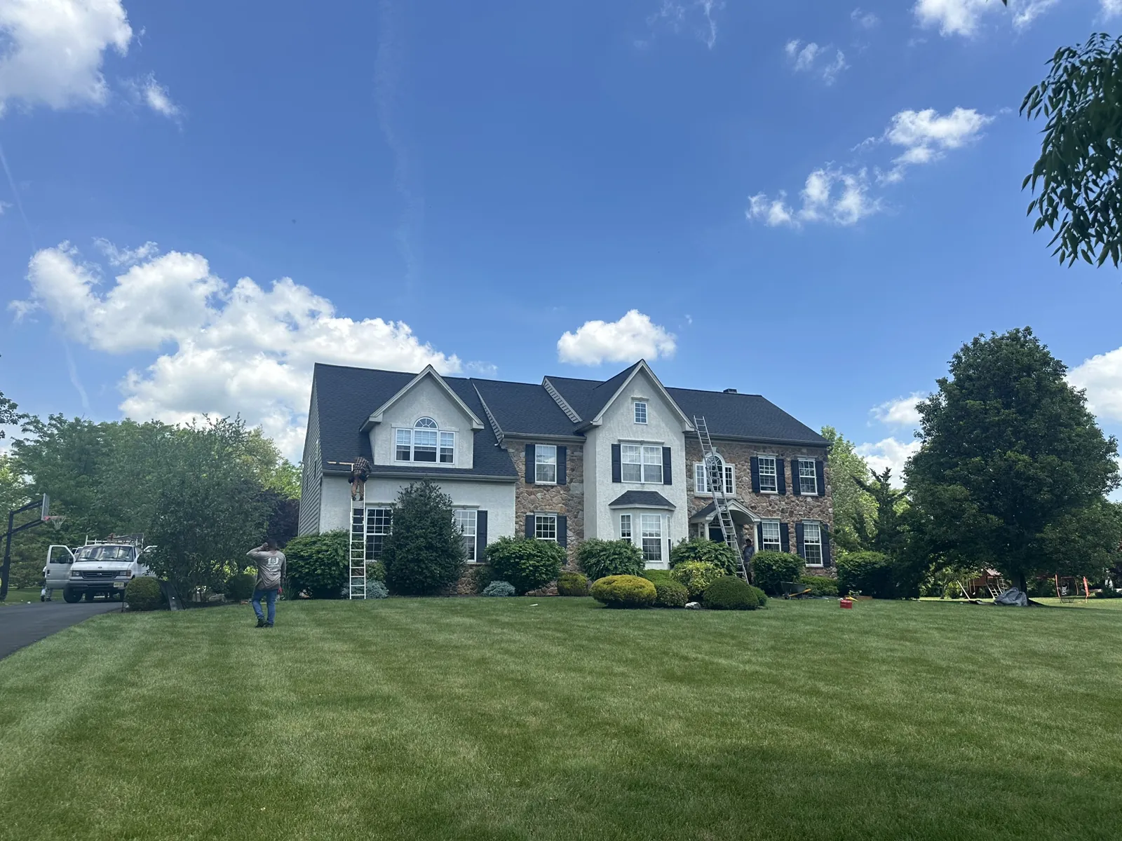 Completed roof replacement on a stone-and-siding colonial