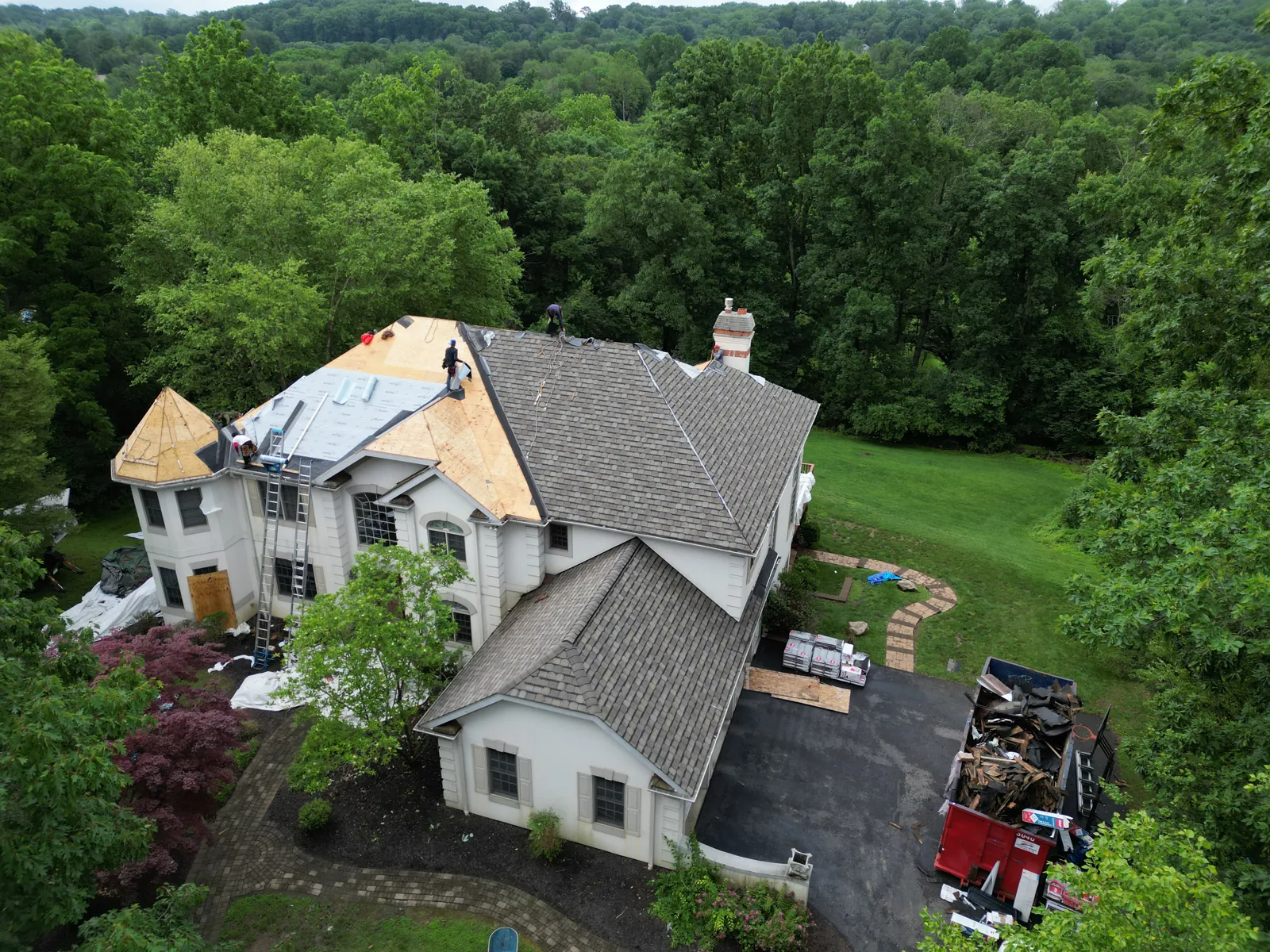 Roof replacement underway on a stone-front home
