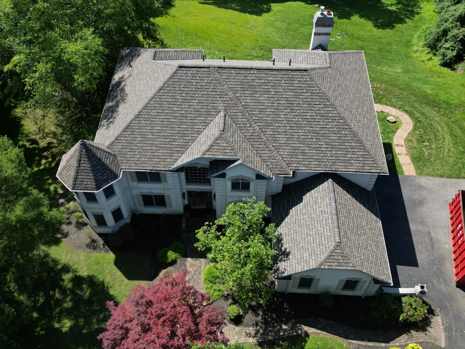 Aerial view of a completed architectural shingle roof on a stone-front home