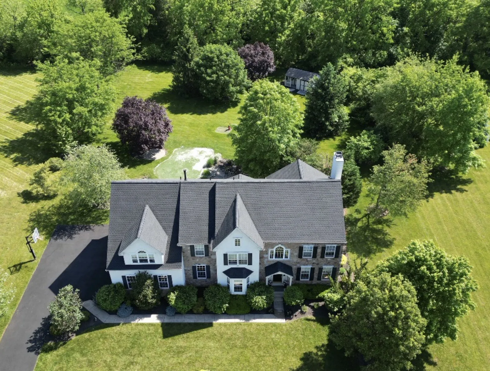 New roof on a white colonial set among mature trees